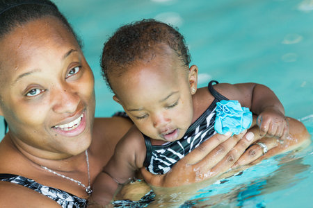 Cute baby girl learning how to swim in indoor pool.の写真素材