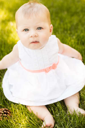 Cute baby girl playing on green grass in the park.の写真素材
