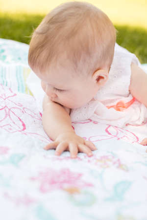 Cute baby girl playing on blanket in the park.の写真素材