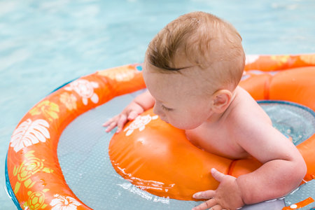 Baby playing in the water at indoor wsimming pool.の写真素材