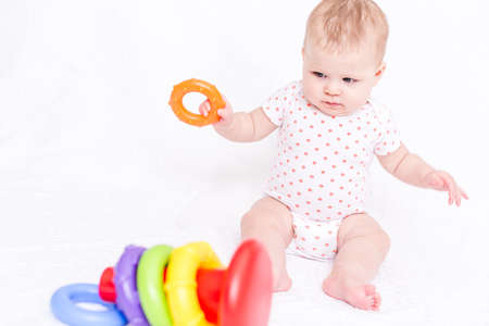 Cute baby girlplaying on a white blanket.の写真素材