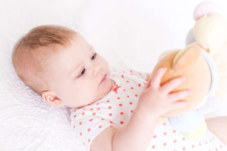 Cute baby girlplaying on a white blanket.の写真素材
