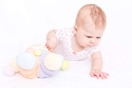 Cute baby girlplaying on a white blanket.の写真素材