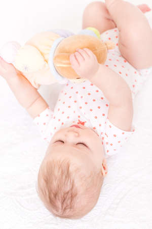 Cute baby girlplaying on a white blanket.の写真素材