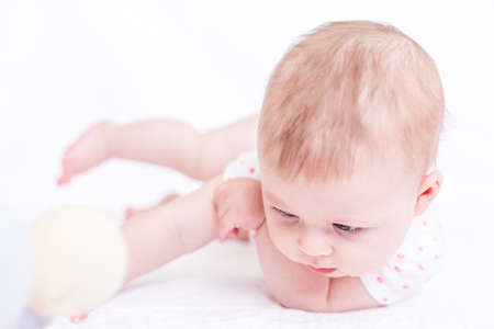 Cute baby girlplaying on a white blanket.の写真素材