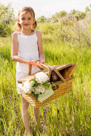 Cute girl with picnic basket in the countryside.の写真素材