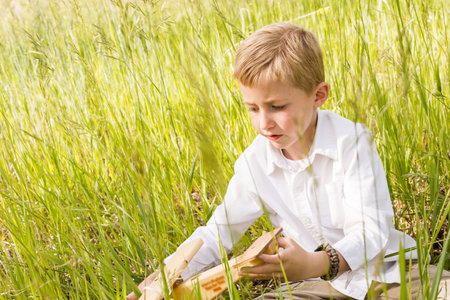 Little boy playing with wooden airplaine  in the countryside.