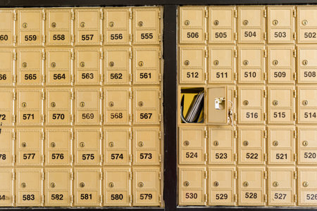 Rows of gold post office boxes with one open mail box の写真素材