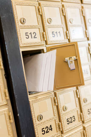 Rows of gold post office boxes with one open mail box の写真素材