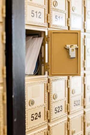 Rows of gold post office boxes with one open mail box の写真素材