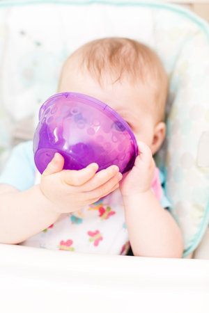 Little girl eating baby food in high chair.の写真素材