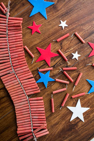 Roll of firecrackers with red, white and blue stars on wood table.の写真素材