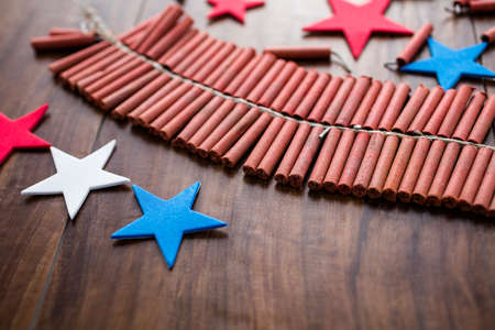Roll of firecrackers with red, white and blue stars on wood table.の写真素材