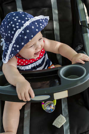 Cute baby girl sitting in her stroller.の写真素材