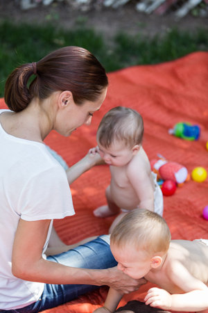 Cute babies playing on the blanket on backyard.