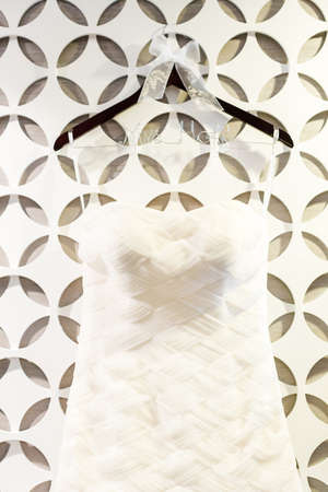 Wedding dress hanging on a white wall with pattern.の写真素材