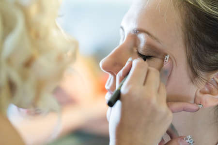 Makeup artist applying make up to the brides face.の写真素材