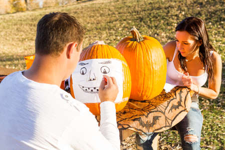 Carving big orange pumpkins for Halloween in late Autumn.の写真素材
