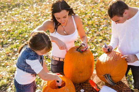 Carving big orange pumpkins for Halloween in late Autumn.の写真素材