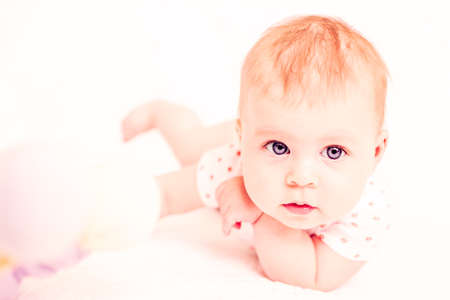Cute baby girlplaying on a white blanket.の写真素材