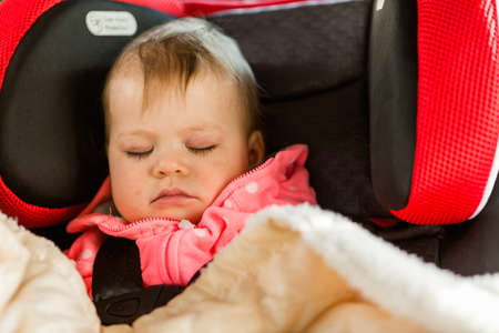 Cute baby girl sleeping in her car seat while traveling in the car.の写真素材