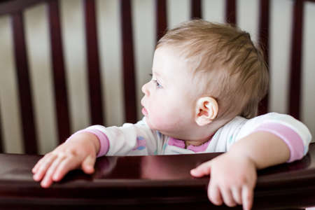 Cute baby girl standing in her crib.の写真素材