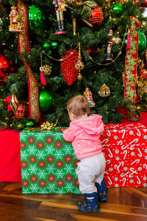 Cute baby girl looking at Christmas presents.の写真素材