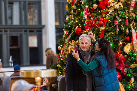 Denver, Colorado, USA-November 23, 2014. Mature couple getting photographed at front of large Christmas tree.のeditorial素材