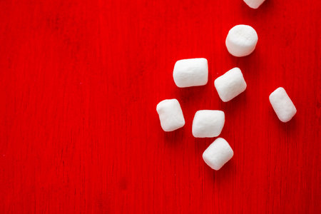 Small round white marshmallows on red backgrouns.