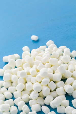 Small round white marshmallows on blue backgrouns.の写真素材