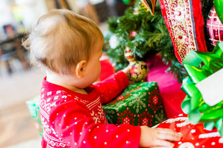 Cute baby girl in Scandinavian red dress next to Christmas tree.の写真素材