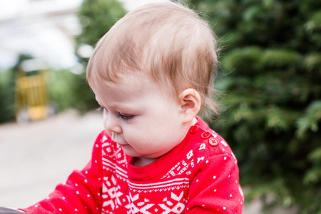 Cute baby girl in red Scandinavian dress at the Christmas tree farm.