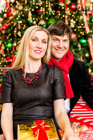 Young couple posing with presents at front of the Christmas tree.の写真素材