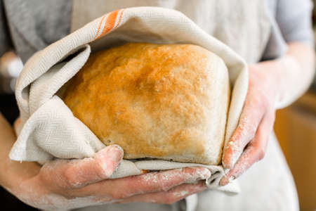 Young baker holding fresh artisan sourdough bread.の写真素材