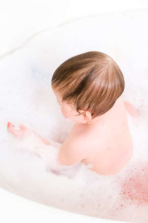 Cute baby girl taking a bath with bubbles.の写真素材