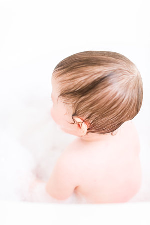 Cute baby girl taking a bath with bubbles.