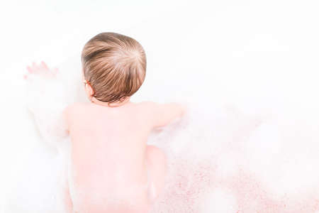 Cute baby girl taking a bath with bubbles.の写真素材