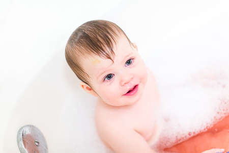 Cute baby girl taking a bath with bubbles.の写真素材