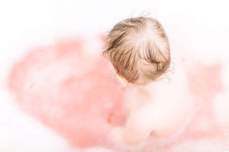 Cute baby girl taking a bath with bubbles.の写真素材