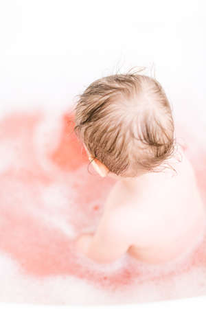 Cute baby girl taking a bath with bubbles.の写真素材