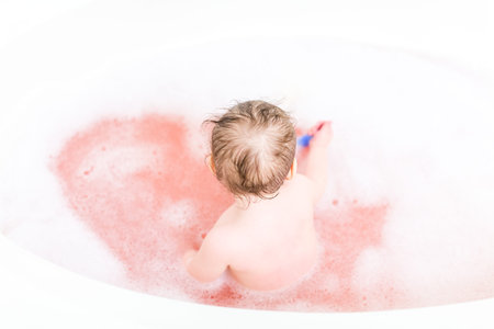 Cute baby girl taking a bath with bubbles.の写真素材