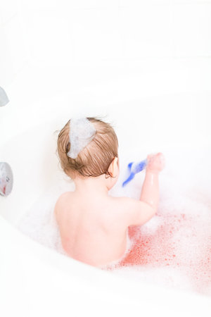 Cute baby girl taking a bath with bubbles.