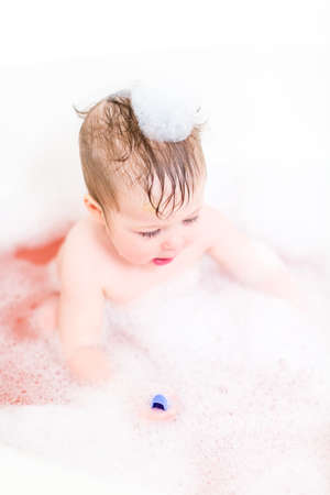 Cute baby girl taking a bath with bubbles.の写真素材