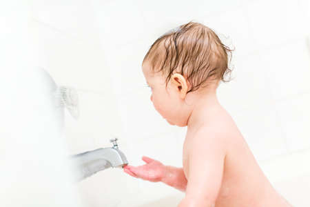 Cute baby girl taking a bath with bubbles.の写真素材