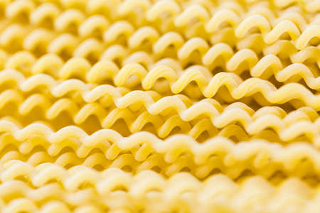 Organic yellow long pasta spirals on a white background.の写真素材