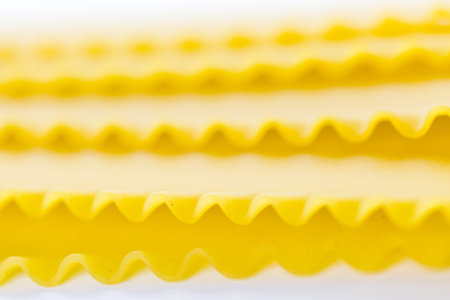 Organic yellow lasagne pasta on a white background.