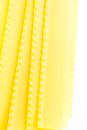 Organic yellow lasagne pasta on a white background.の写真素材