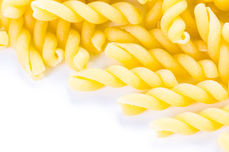 Organic yellow gemelli pasta on a white background.