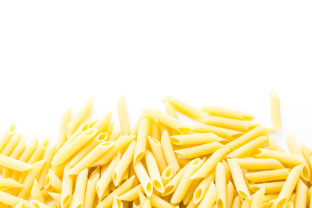 Organic yellow rigate pasta on a white background.の写真素材