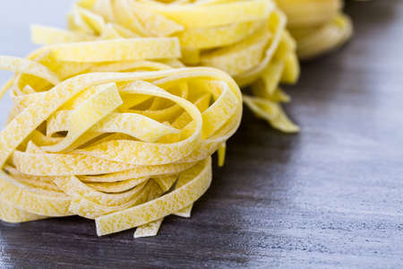 Organic fettuccine nests pasta on wood board.の写真素材